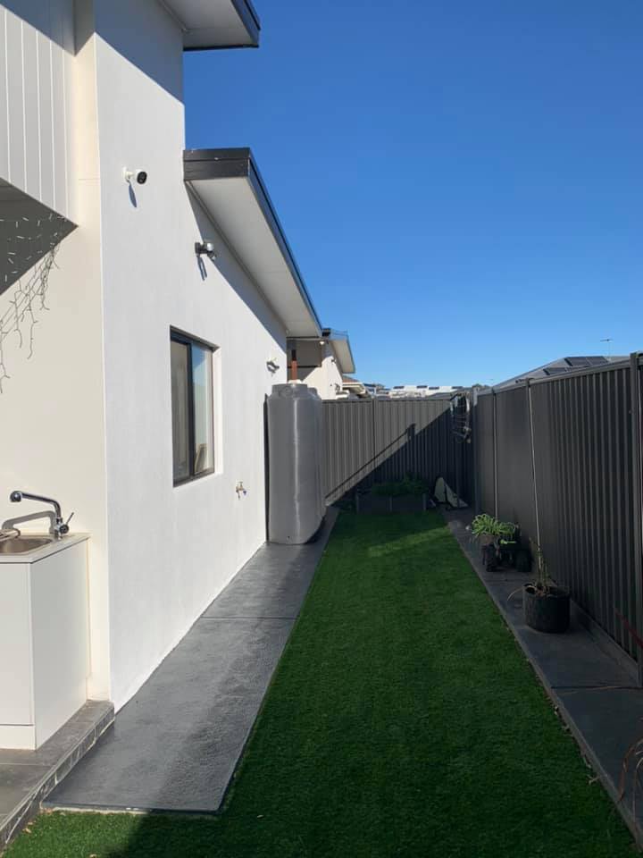 Picture of backyard in between fence and white painted wall