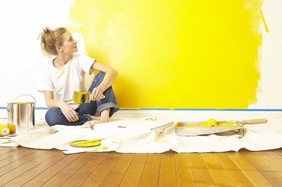 Hire a painter or DIY, girl doing a yellow paint on wall
